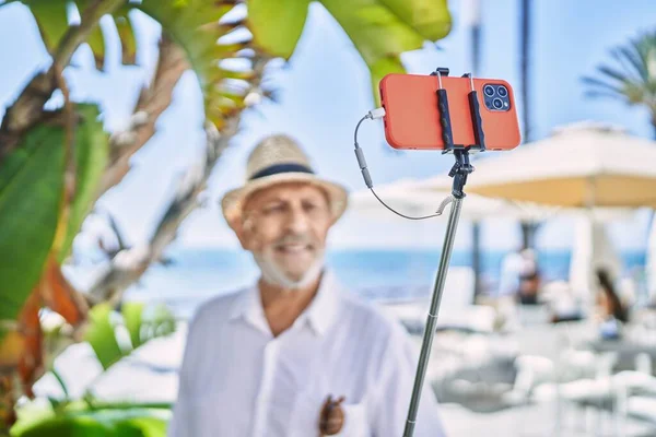 모자를 바닷가에서 스마트폰으로 셀카를 만드는 — 스톡 사진