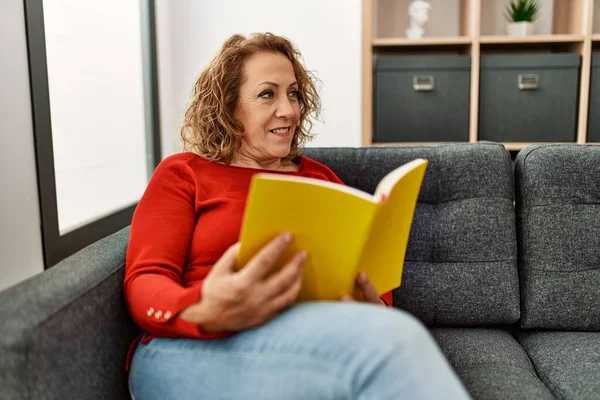 Orta Yaşlı Beyaz Kadın Kitap Okuyor Evdeki Kanepede Oturuyor — Stok fotoğraf