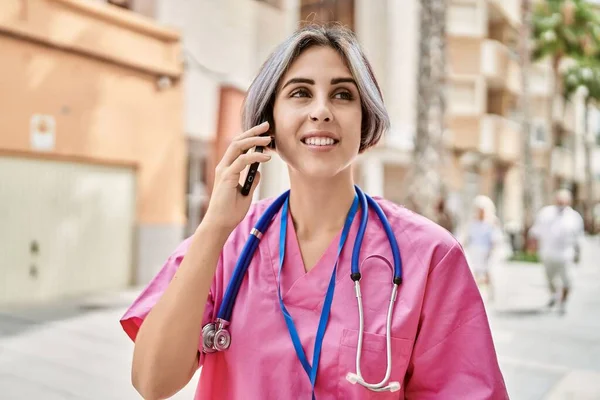 在城市里 年轻的高加索医生女人高兴地在智能手机上交谈 — 图库照片