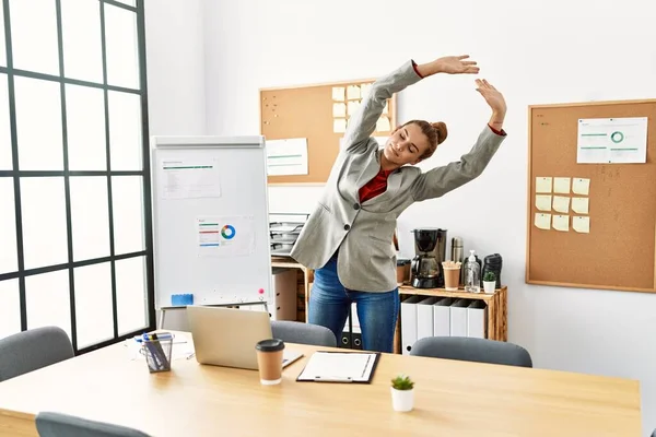 Young woman business worker stretching at office