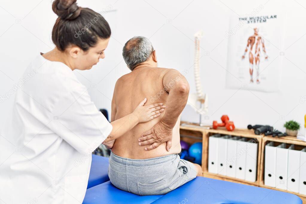 Physiotherapist and patient on back view having rehab session at clinic