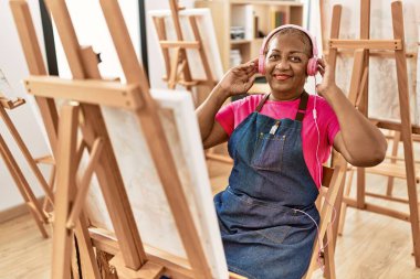 Sanat stüdyosunda müzik dinleyen kıdemli Afro-Amerikan kadın.