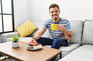 Genç İspanyol adam evde kahvaltı ederken kendine güveniyor.