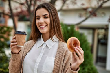 Genç İspanyol iş kadını gülümseyerek şehirde kahvaltı yapıyor..