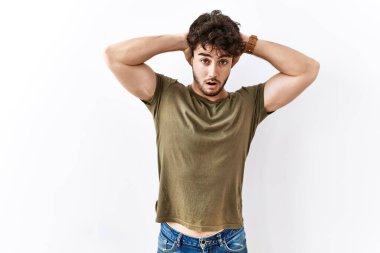 Hispanik adam yalnız beyaz arka planda duruyor. Deli ve korkmuş, elleri başının üstünde, korkmuş ve ağzı açık şoktan şaşırmış. 