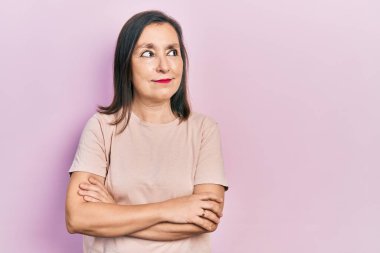 Orta yaşlı, kollarını kavuşturmuş, gülümseyen, yan bakıp düşünen İspanyol bir kadın.. 