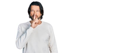 Orta yaşlı, günlük kıyafetler giyen beyaz bir adam sessiz olmak istiyor, dudakları parmaklarıyla. sessizlik ve gizli konsept. 