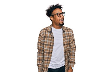 Sakallı, sıradan kıyafetler ve gözlüklü, yüzünde gülümseme, doğal bir ifade olan Afro-Amerikan genç bir adam. Kendinden emin gülen. 