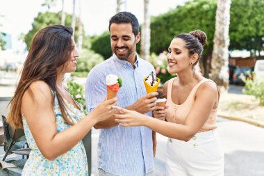 Üç İspanyol arkadaş gülerek şehirde dondurma yiyor..
