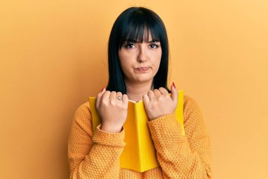 Genç İspanyol kadın kitabı kuşkucu ve gergin tutuyor, sorun yüzünden surat asıyor. negatif kişi. 