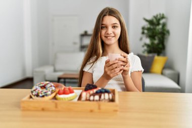 Çok tatlı bir kız kahvaltısını evde, masada yapıyor.