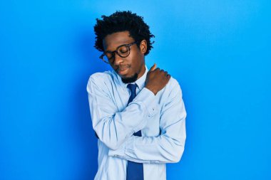 Genç Afro-Amerikan adam iş kıyafetleri giyip kendine sarılıyor mutlu ve pozitif, kendinden emin gülümsüyor. Sevgi ve özgüven. 