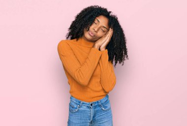 Genç Afro-Amerikalı kız günlük kıyafetler giyip uyuyordu. Yorgundu, hayal kuruyordu ve elleriyle poz veriyordu. Gözleri kapalıydı.. 