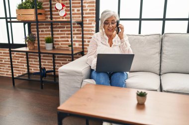Evde bilgisayarla konuşan orta yaşlı bir kadın.