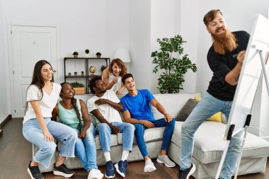 Bir grup genç arkadaş gülümseyerek evde çizim oyunu oynuyorlar..