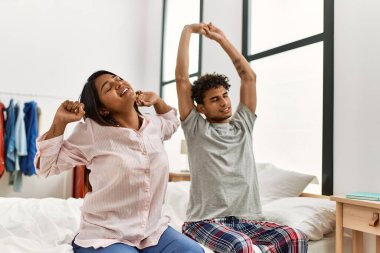Genç Latin çift, yatak odasındaki yatakta esniyor ve kollarını esnetiyorlar..