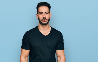 Sakallı, sıradan siyah tişörtlü İspanyol bir adam. Yüzünde ciddi bir ifadeyle rahatlamış. Basit ve doğal bir şekilde kameraya bakıyorsun.. 