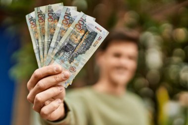 Genç İspanyol gülümseyen adam Peru tabanlı banknotları şehirde tutarken mutlu..