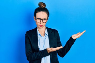 Avuç içleri açık, elinde şüpheci ve gergin bir şey tutan, sorun yüzünden kaşlarını çatan İspanyol bir kız. negatif kişi. 