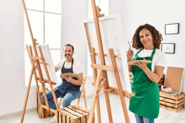 Resim stüdyosunda gülümseyen iki orta yaşlı öğrenci..