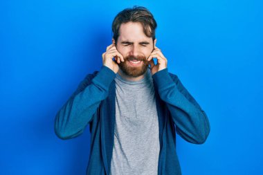 Gürültülü müzik sesi için kulaklarını parmaklarıyla kapatan sıradan bir kazak giyen beyaz bir adam. sağır kavramı. 