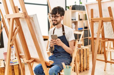 Sanat stüdyosunda akıllı telefon çizimi yapan genç bir İspanyol sanatçı..