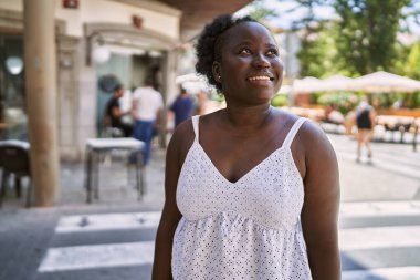 Genç Afrikalı Amerikalı kadın gülümseyerek şehirde mutlu mesut duruyor..