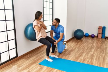 Latin erkek ve kadın fizyoterapist üniforması giyiyorlar rehabilitasyon merkezinde sağlıklı top kullanıyorlar.