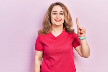 Orta yaşlı, günlük kıyafetler giyen beyaz bir kadın başarılı bir fikri işaret ediyor. Heyecanlı ve mutlu. Bir numara.. 