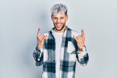 Modern boyalı saçlı, sıradan tişörtlü, çılgın bir ifadeyle bağıran, elleri havada rock sembolü yapan genç İspanyol bir adam. Müzik yıldızı. ağır kavram. 