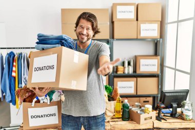 Gönüllü olarak bağış kutusunu tutan yakışıklı, orta yaşlı bir adam. Karşılama ve hoş geldin demek için gülümseyerek el sıkışır. başarılı iş. 