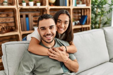 Kanepede oturan genç latin çift evde sarılıyorlar..