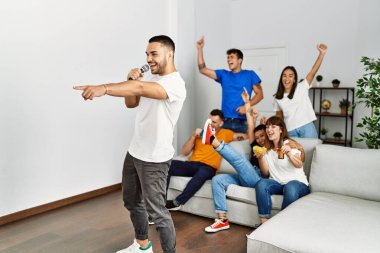 Bir grup genç arkadaş evde mikrofon kullanarak şarkı söylüyor..