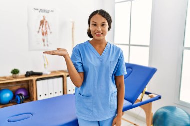 Güzel İspanyol fizyoterapist kadın ağrı kesici kliniğinde gülümseyen, mutlu bir sunum yapan ve avuç içi kameraya bakan.. 