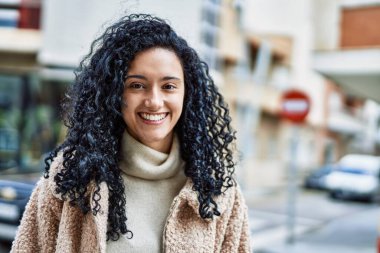 Sokakta kendinden emin gülümseyen genç İspanyol kadın.