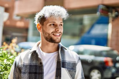 Genç İspanyol adam gülümseyerek şehirde mutlu mesut dikiliyor..