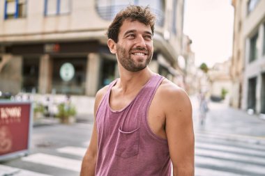 Genç İspanyol adam gülümseyerek şehirde mutlu mesut dikiliyor..