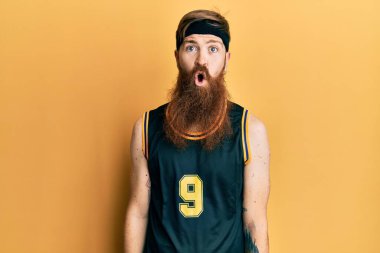 Kızıl saçlı, uzun sakallı basketbol forması giyen, korkmuş ve şok olmuş bir adam.. 