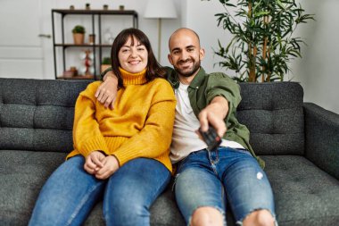 Genç İspanyol çift mutlu bir şekilde gülümsüyor. Evdeki kanepede oturup film izliyorlar..