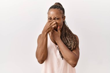 Saçları örgülü siyah bir kadın, izole edilmiş arka planda duruyor. Kokuşmuş ve iğrenç bir koku alıyor. Dayanılmaz bir koku. Kötü kokuyor. 