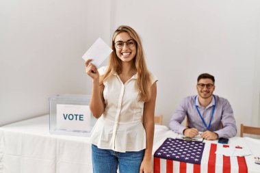 Genç Amerikalı seçmen kadın seçmen kolejinde oy verirken mutlu gülümsüyor..