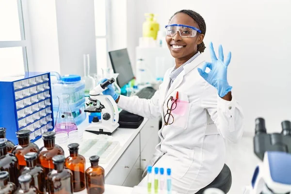 科学研究所で働いているアフリカの女性は 指でOkサインをし 優れたシンボルをジェスチャーで笑顔 — ストック写真
