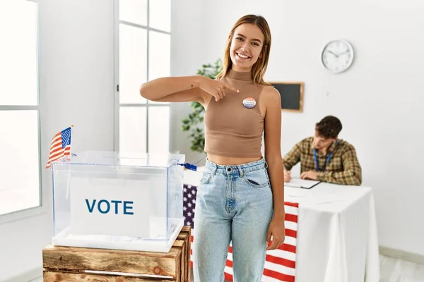 若いアメリカの有権者の女性は笑顔幸せなポインティングで指でバッジに選挙大学 — ストック写真