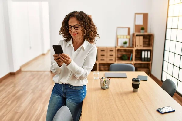 Orta Yaşlı Spanyol Kadın Ofisteki Akıllı Telefonu Kullanarak Gülümsüyor — Stok fotoğraf