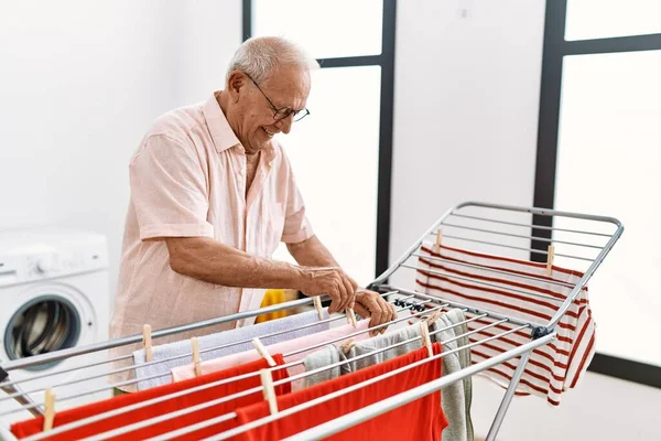 Hombre Mayor Sonriendo Confiado Colgando Ropa Tendedero Sala Lavandería — Foto de Stock