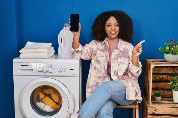 Young African American Woman Doing Laundry Using Smartphone Smiling Happy — Fotografia de Stock