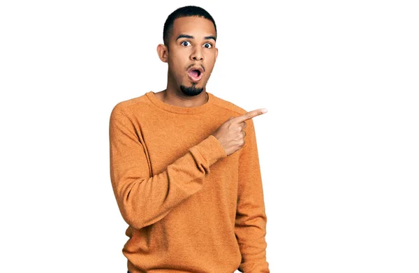 若いアフリカ系アメリカ人男性を着てカジュアルな服驚きを指して指で側に 口を開けて驚いて表現 — ストック写真