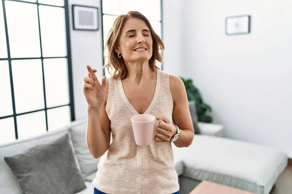 Middle Age Woman Drinking Cup Coffee Home Gesturing Finger Crossed — Photo