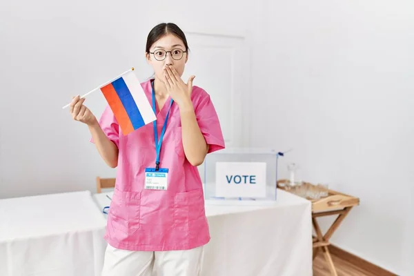 Молодая Азиатская Медсестра Выборах Держащая Российский Флаг Прикрывающий Рот Рукой — стоковое фото