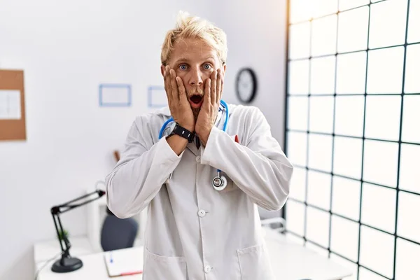 Jonge Blonde Man Draagt Doktersuniform Stethoscoop Kliniek Bang Geschokt Verrast — Stockfoto